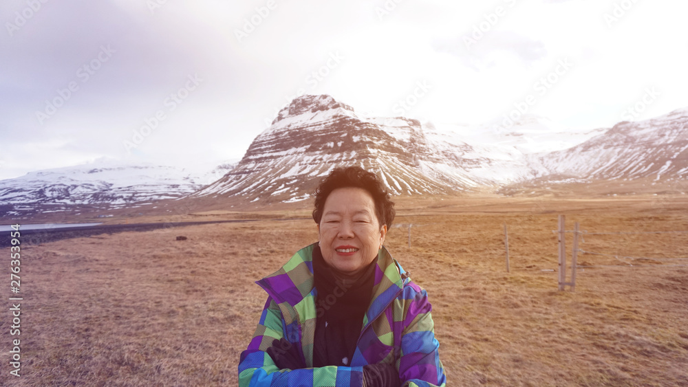 Happy Asian senior woman fun trip in Europe photo with Iceland glacier