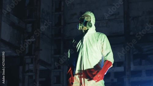 Young funny man in protection wear and gas mask dancing and having fun in the courtyard of abandoned building. Post-apocalyptic. Last man on Earth.