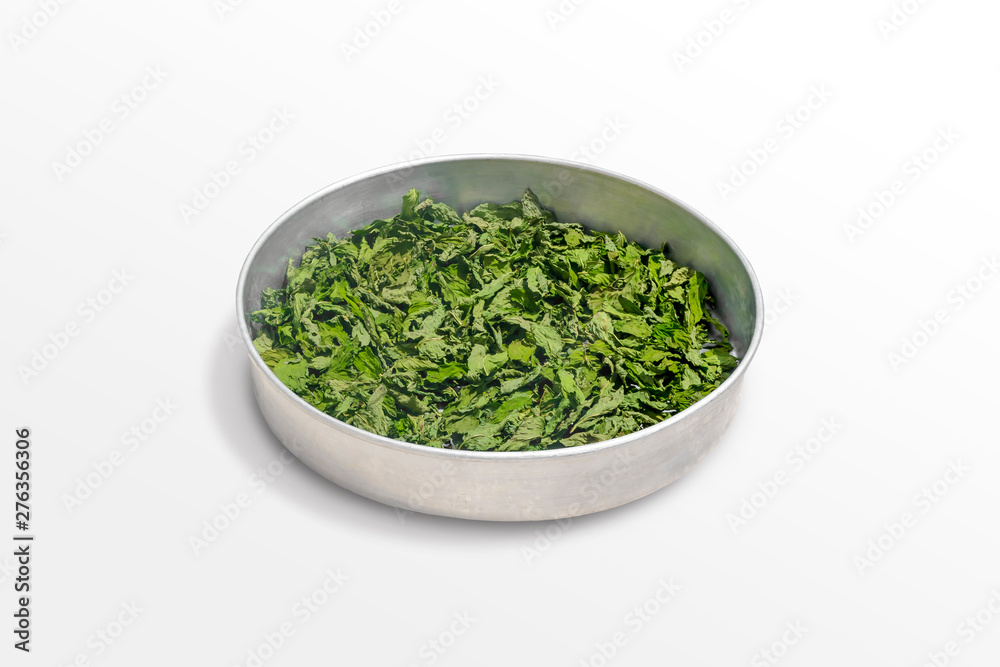 Dry healing mint leaves on a metal bowl isolated on white background