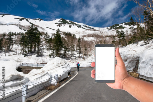 hand hold mobile phone with a road of snow wall japan alps mountain, Japan.