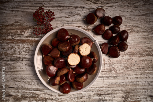 group of tasty chestnuts next to a bowl