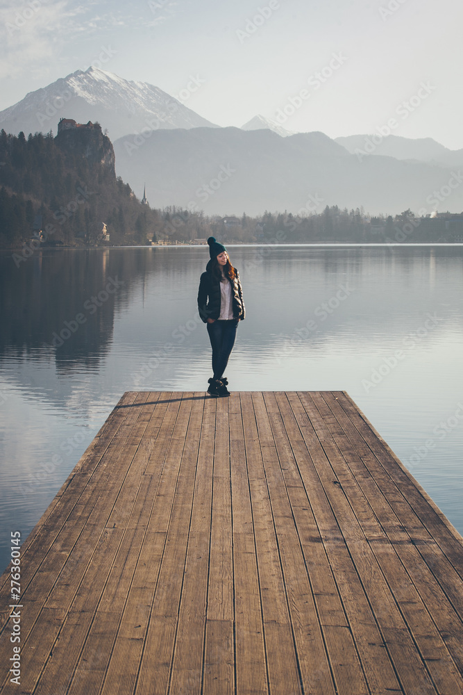 Young lady on the lake pier, early morning.