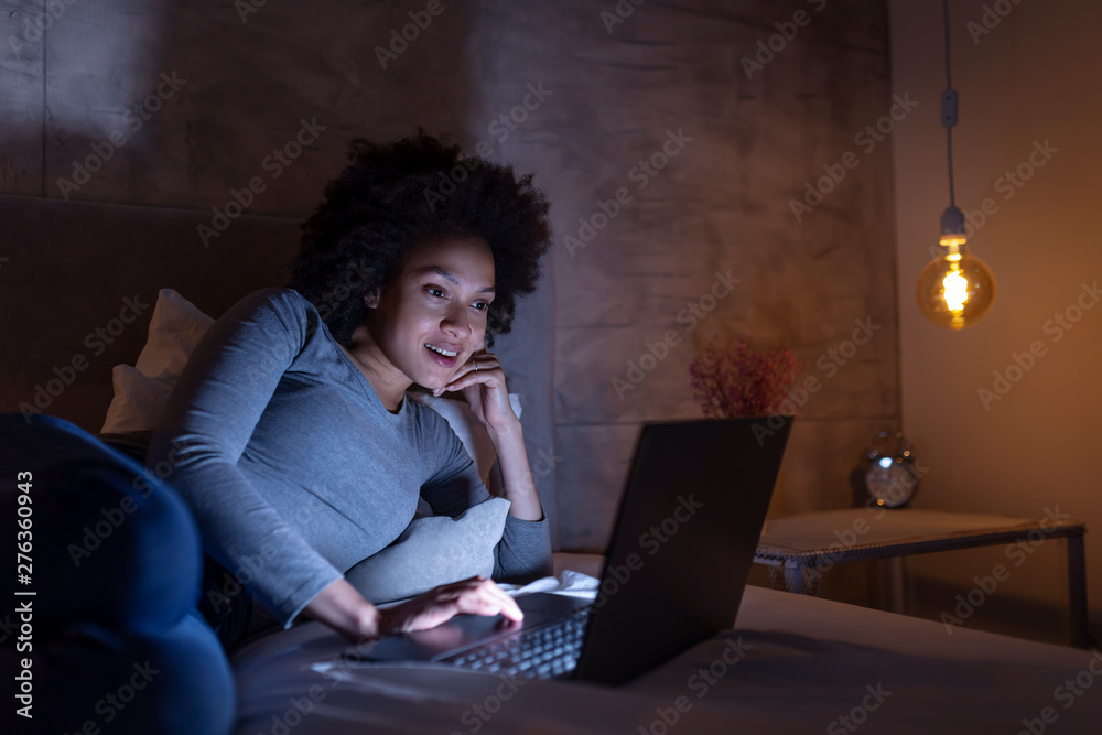 Woman lying in bed having video call on a laptop computer Woman lying in bed having video call on a laptop computer