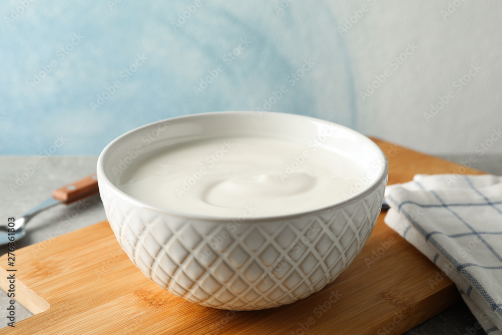 Composition with yogurt in bowl on grey table against blue background Composition with yogurt in bowl on grey table against blue background