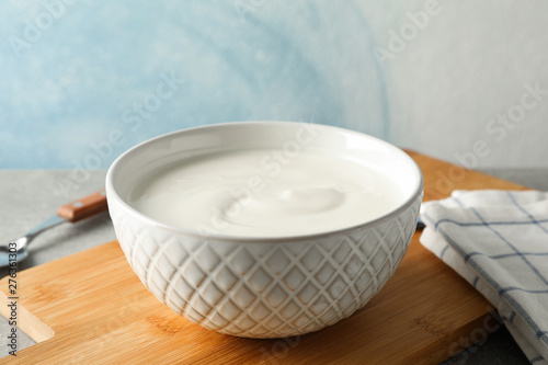 Composition with yogurt in bowl on grey table against blue background