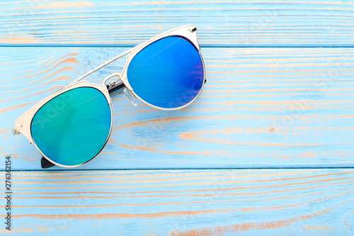 Modern sunglasses on blue wooden table