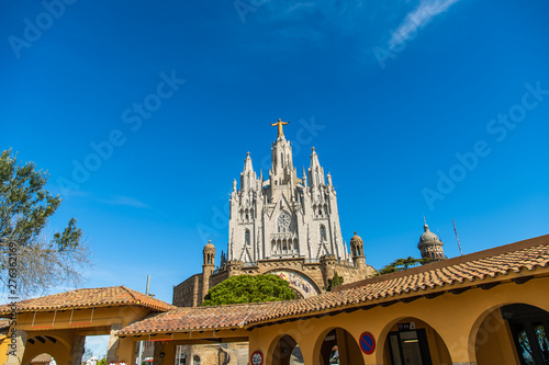  Tibidabo Cathedral. Temple of the Sacred Heart of Jesus at Mount Tibidabo. High pine-tree tree and blue sky with cloud of summer day. Famous landmark in Catalonia, Espana. photo