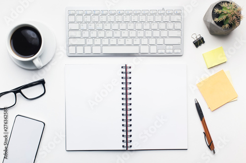 Office table with open notepad and other accessories on white