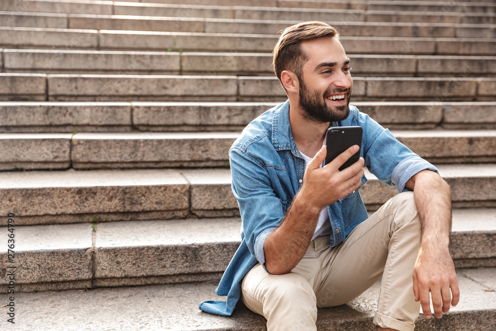 Smiling young man sitting on stairs outdoors Smiling young man sitting on stairs outdoors