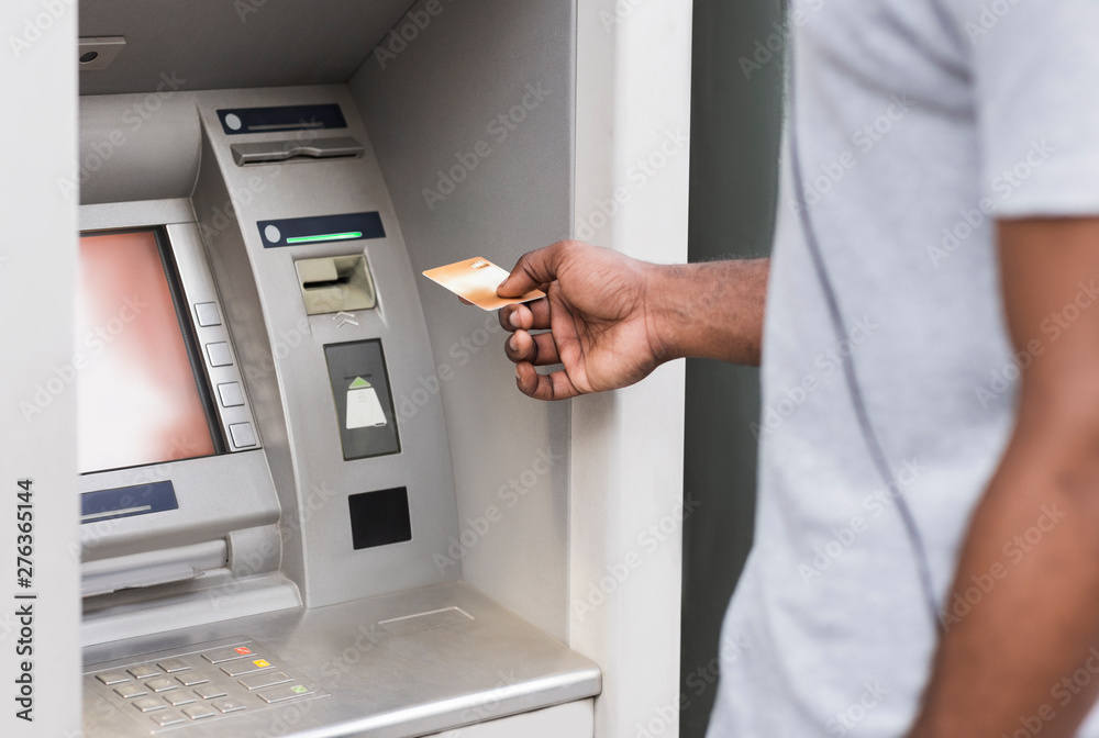 Hand of a man with gold credit card using ATM outdoor Hand of a man with gold credit card using ATM outdoor