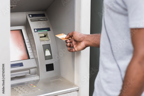 Hand of a man with gold credit card using ATM outdoor