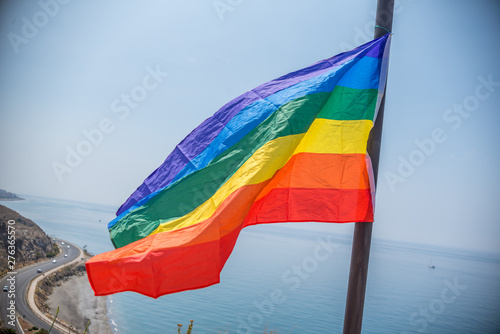 Pride flag with lgbti colors waving in the air in front of the sea