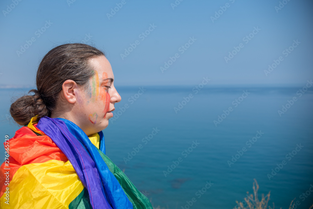 Fototapeta premium Young girl with face painted and with flag with colors of pride