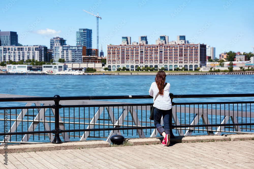 Young redhead female watching the scenery of Montreal city and the Saint Lawrence river on a sunny summer day in Quebec, Canada.