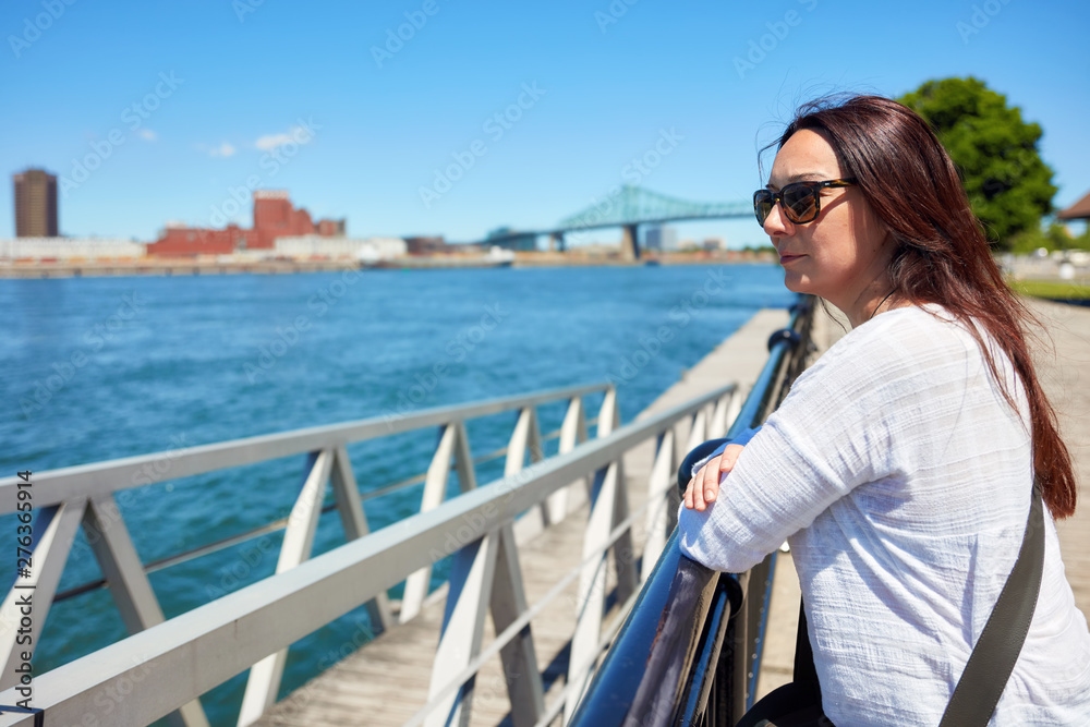 Redhead woman watching the scenery of Montreal city and the Saint Lawrence river on a sunny summer day in Quebec, Canada.