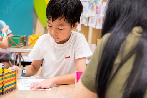 kids are painting picture with color pencil with their teacher in the classroom to learn paint skill. they are practicing the imagine lesson workshop. photo