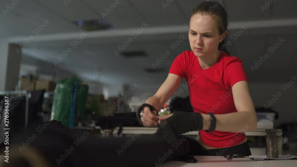 Cyber punk fashion designer at work in her studio cutting pattern - Caucasian white woman wearing red t-shirt and black gloves with scissors hanging over her chest Cyber punk fashion designer at work in her studio cutting pattern - Caucasian white woman wearing red t-shirt and black gloves with scissors hanging over her chest