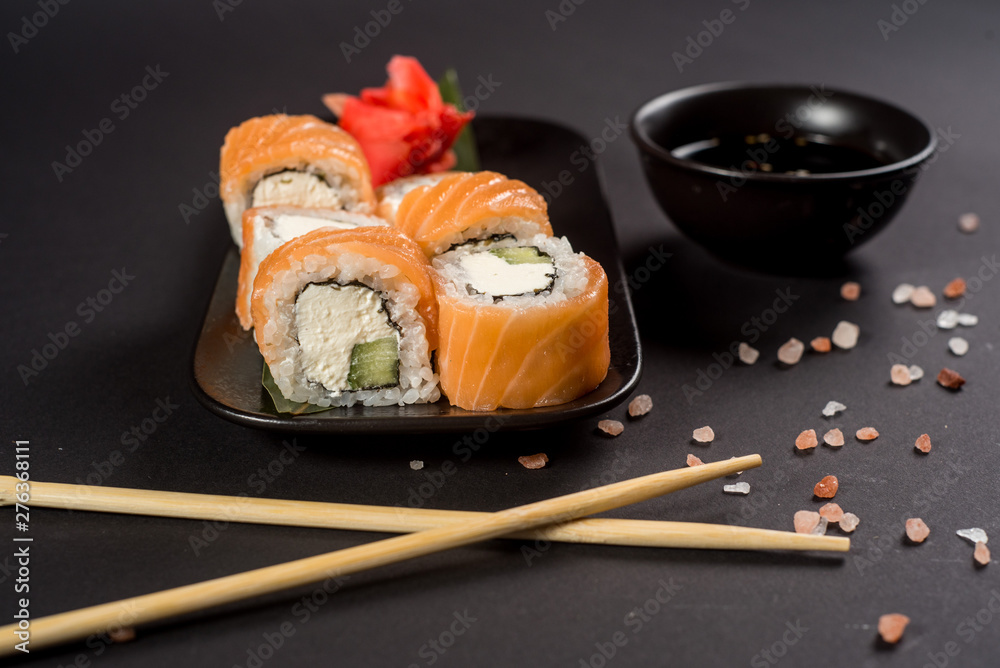 Close up sushi rolls in a black plate on dark background Close up sushi rolls in a black plate on dark background