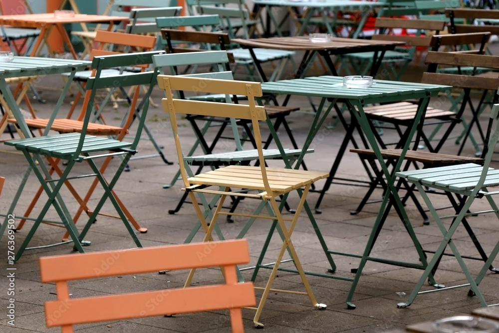 Colorful wooden chairs and tables in a park or cafe outdoor. Selective focus.
