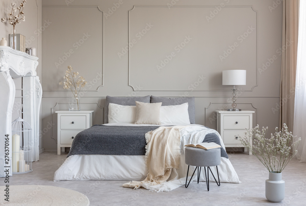 Flowers on white wooden nightstand table in luxury bedroom interior with king size bed - obrazy, fototapety, plakaty 