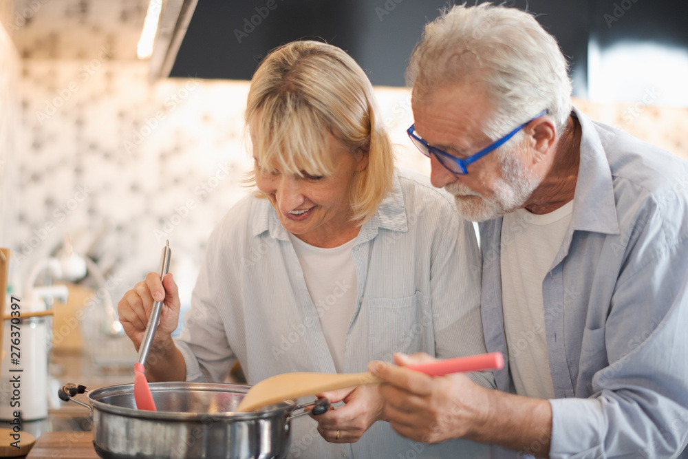 Closed up senior Caucasian couple are cooking and testing a meal or health food which smile and felling happy in kitchen at home. Old man and woman look meal. Senior family activity at home concept. Closed up senior Caucasian couple are cooking and testing a meal or health food which smile and felling happy in kitchen at home. Old man and woman look meal. Senior family activity at home concept.