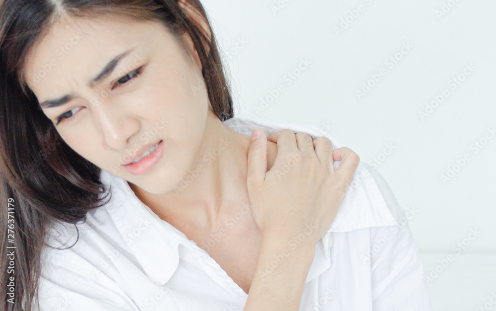 Asian women wear white pajamas in the bedroom. She has pain in the neck area. Asian women wear white pajamas in the bedroom. She has pain in the neck area.