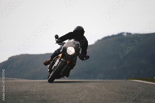 One, classic, stock motorbike is cornering on the mountain road.
