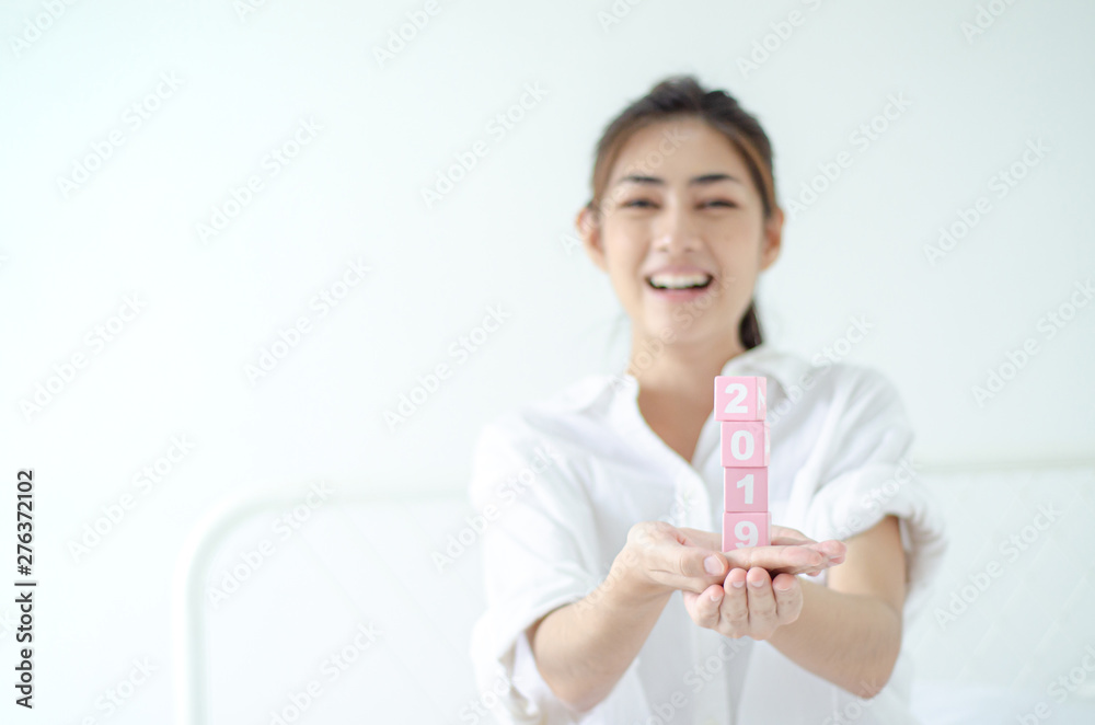 Small pink square wooden box with numbers in Asian women hands.Do not focus on the main object of this image. Small pink square wooden box with numbers in Asian women hands.Do not focus on the main object of this image.