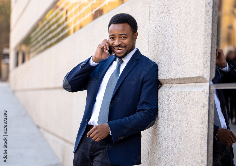 Portrait of handsome african american businessman walking in the city talking on mobile phone