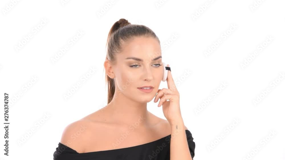 Beauty concept. The woman is using a sponge to apply powder on her face. Beauty concept. The woman is using a sponge to apply powder on her face.