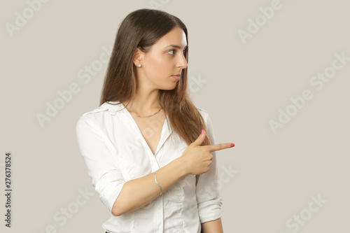 Beautiful attractive young woman portrait. Business woman pointing the finger to the side, studio shot with copy space