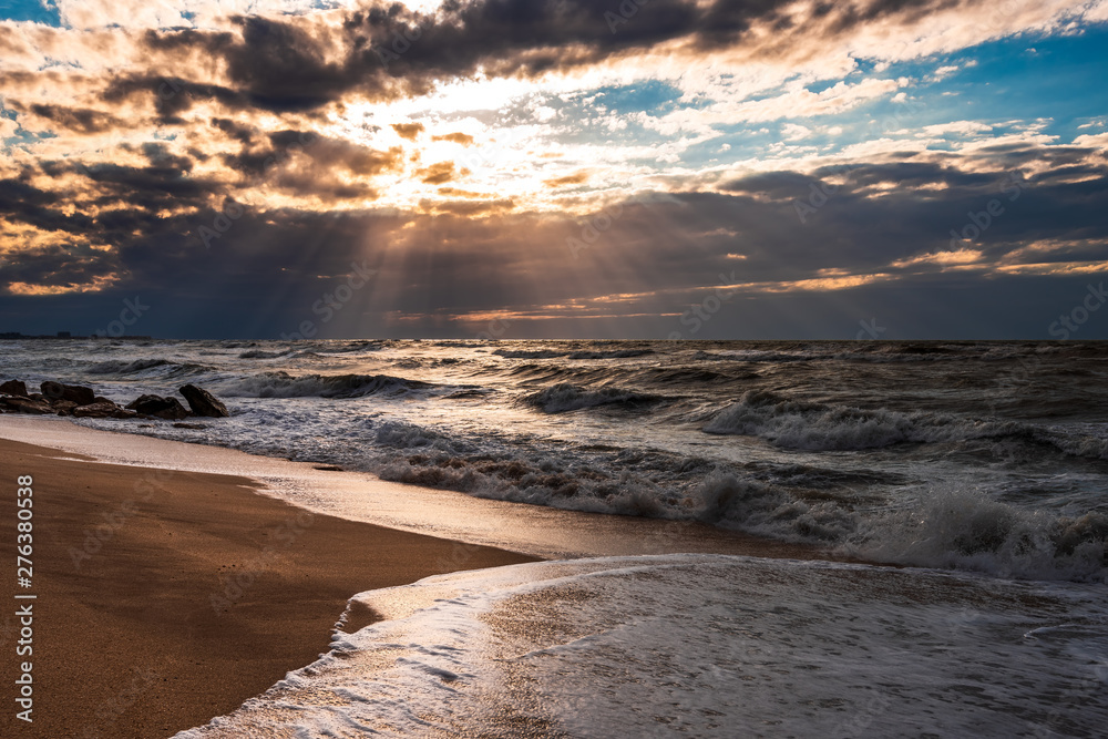 A beach with golden sand, small waves and a beautiful dramatic sky