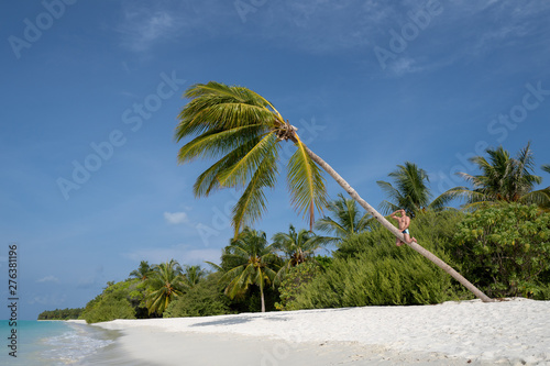 A young guy climbed a palm tree on an uninhabited island to look for help in the distance.