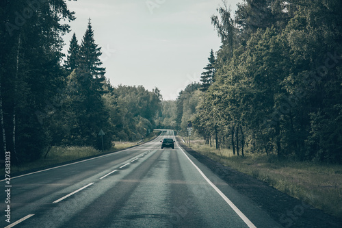 Автомобили проезжающие по асфальтированной дороге, в сельской местности. В московской области, среди леса.