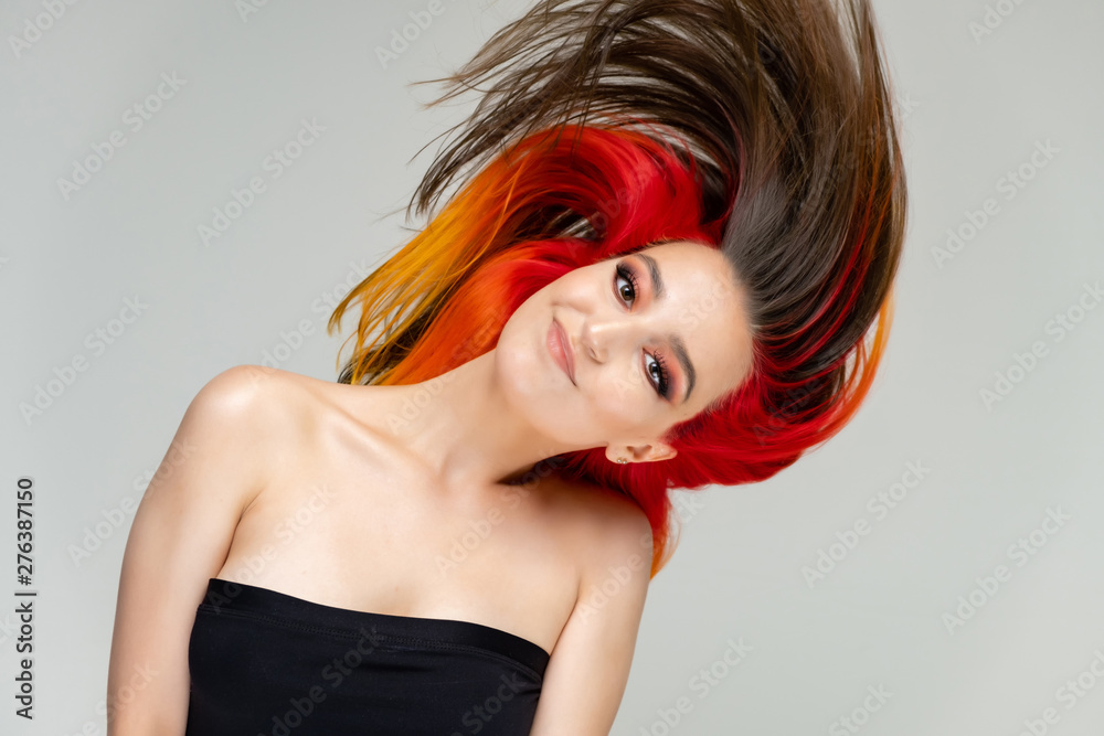 A close-up portrait photo of a fashionable hairstyle red-yellow in studio on a white background. The pretty brunette model with beautiful make-up has beautiful flowing colorful hair. A close-up portrait photo of a fashionable hairstyle red-yellow in studio on a white background. The pretty brunette model with beautiful make-up has beautiful flowing colorful hair.