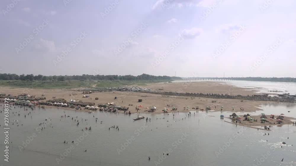 aerial slider shot of crowds of people have gathered to take a swim , with wooden bungalows spread over sand beach. Traffic jam on bamboo bridge as backdrop aerial slider shot of crowds of people have gathered to take a swim , with wooden bungalows spread over sand beach. Traffic jam on bamboo bridge as backdrop