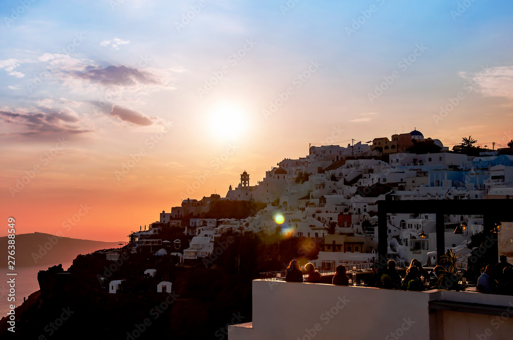 Beautiful sunset overlooking the Aegean Sea, island of Santorini, Greece, Europe. Evening view of the city with classical white Greek architecture, churches, houses. Famous travel destination