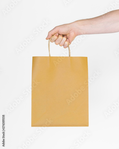 men's hand holding paper shopping bag, shopping concept