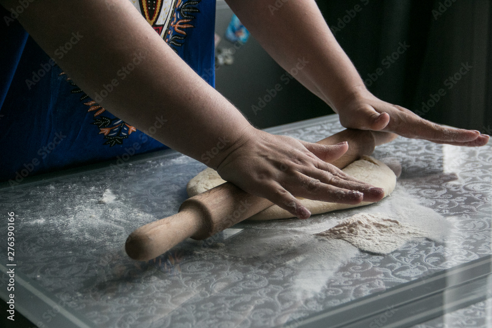 Women's hands rolling a rolling pin on a glass table dough Women's hands rolling a rolling pin on a glass table dough