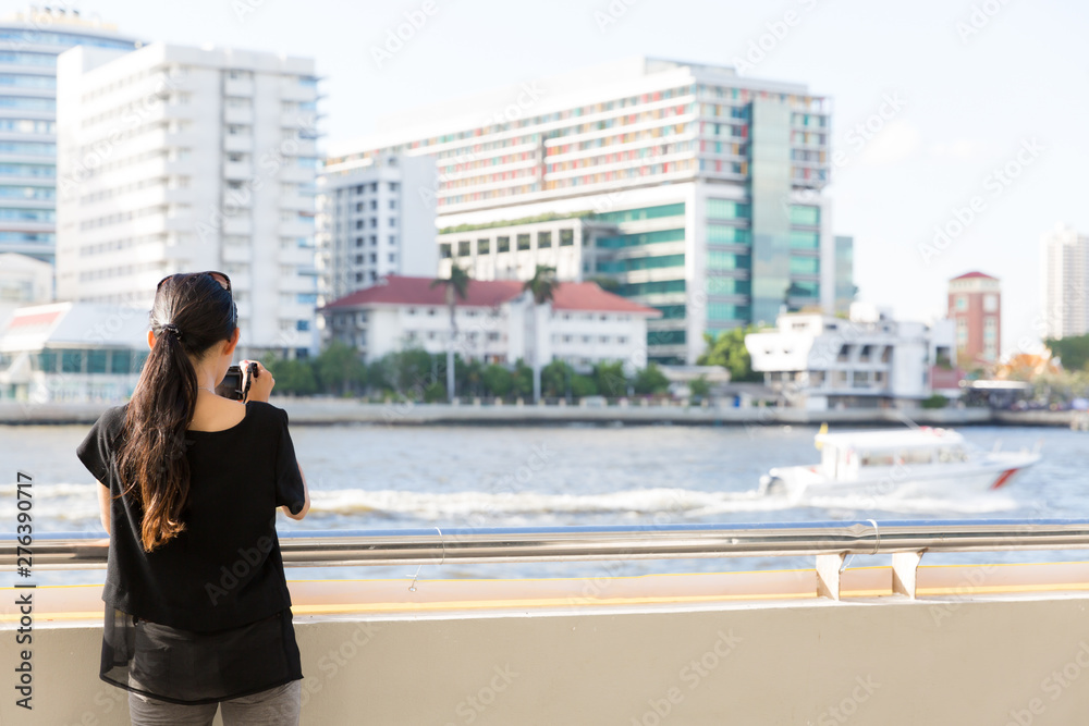 Pretty female photographer taking a picture of Chao Phraya River
