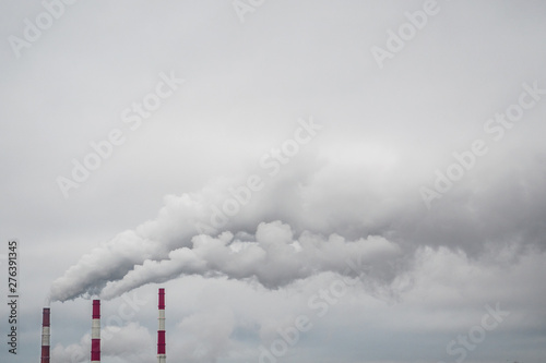 Environmental and air pollution, ecological problems concept. Smoke from factory chimneys against a gray cloudy sky