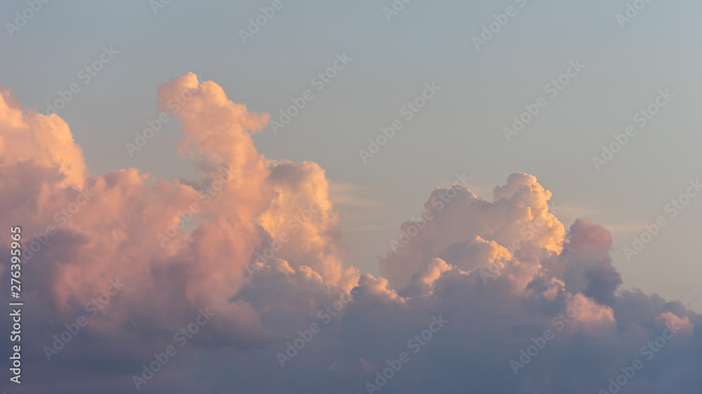 Close up view of beautiful colored cumulus fluffy clouds with pink and purple hues in the blue sky at sunset background - obrazy, fototapety, plakaty 