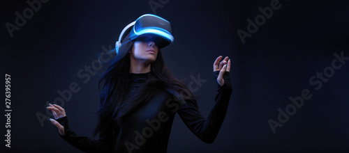 Beautiful woman with flowing hair in futuristic dress over dark background. Girl in glasses of virtual reality. Augmented reality, science, future technology, robots and people concept. VR. photo
