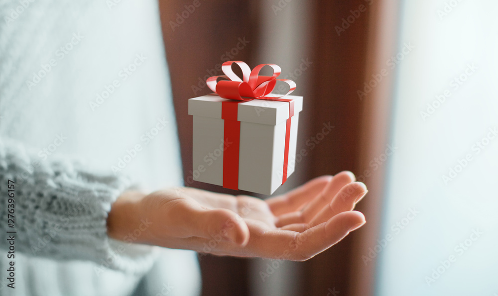 Woman holding gift box with bow - obrazy, fototapety, plakaty 