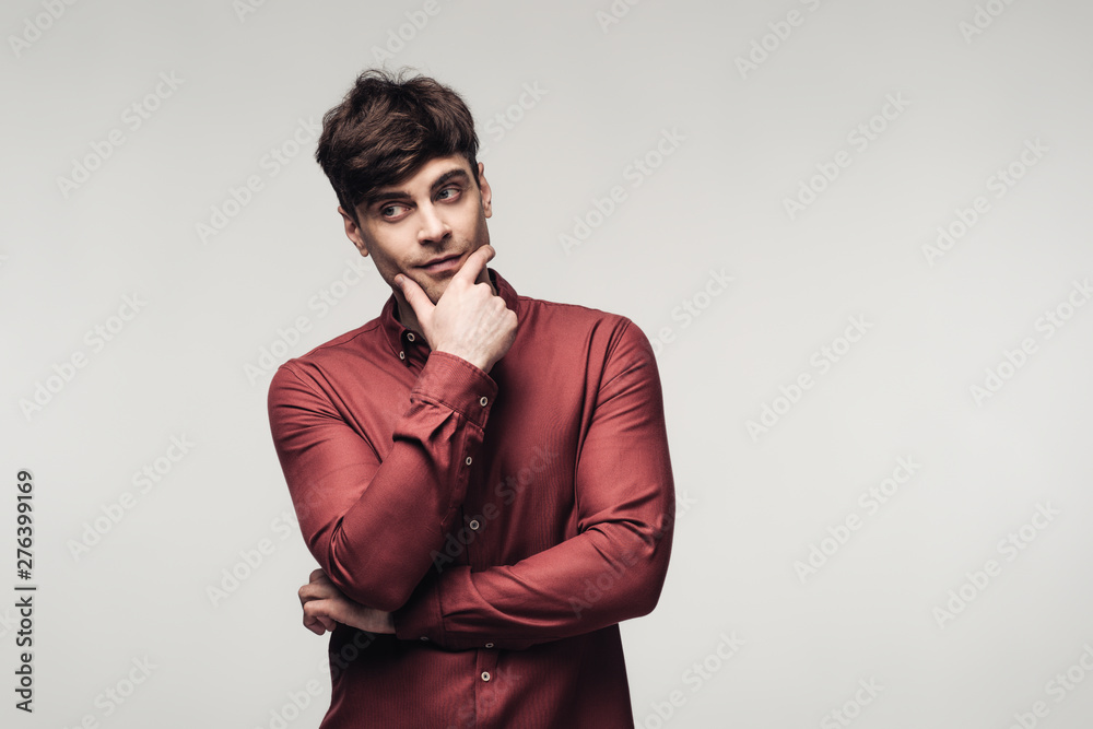Obraz premium dreamy man looking away while holding hands near face isolated on grey