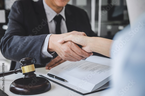 Handshake after good cooperation, Businesswoman Shaking hands with Professional male lawyer after discussing good deal of contract in courtroom, Concepts of law, Judge gavel with scales of justice