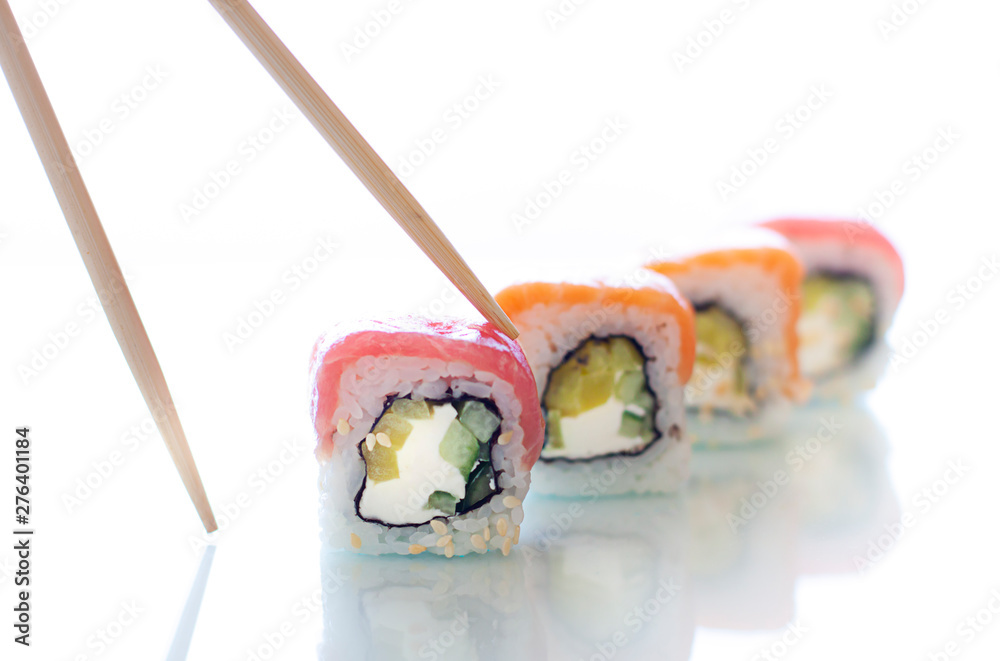 Sushi rolls with chopsticks on the white background. Japanese food close up Sushi rolls with chopsticks on the white background. Japanese food close up