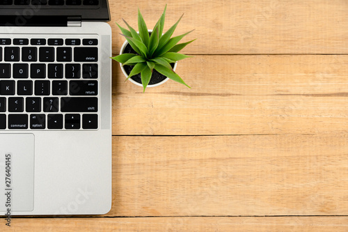 Wood office work space desk table with laptop and blank picture frame, small plant, pencil. Top view with copy space, flat lay.