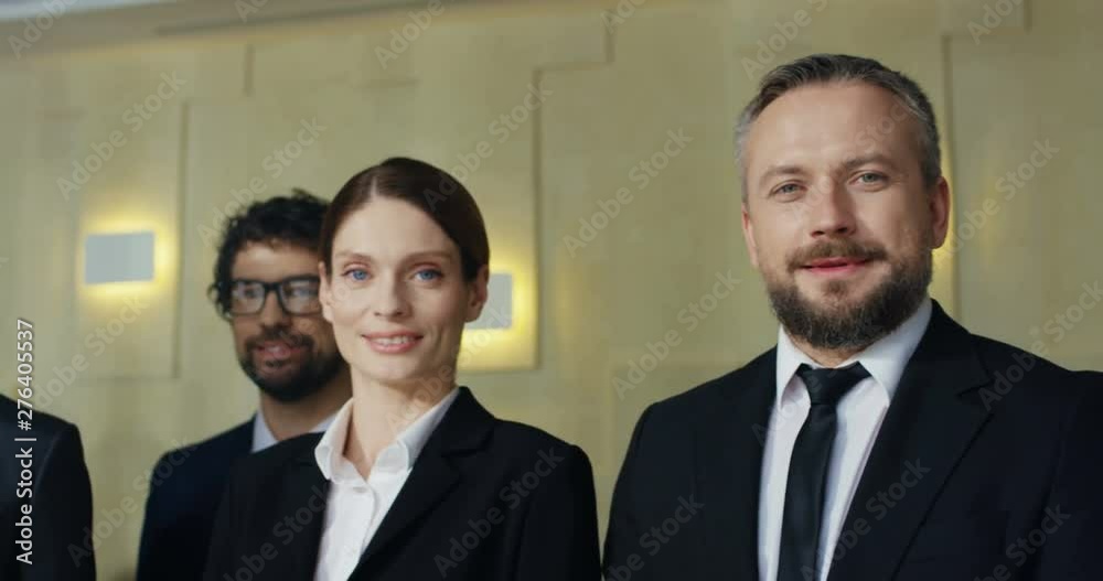 Close up of the Caucasian and African American male and female business people standing all together at the metting and posing smiling to the camera. Close up of the Caucasian and African American male and female business people standing all together at the metting and posing smiling to the camera.