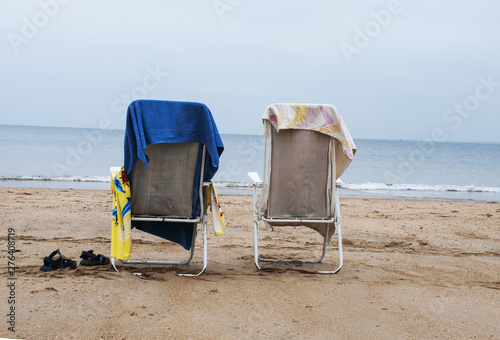 Empty hammocks on the beach with colorful towels